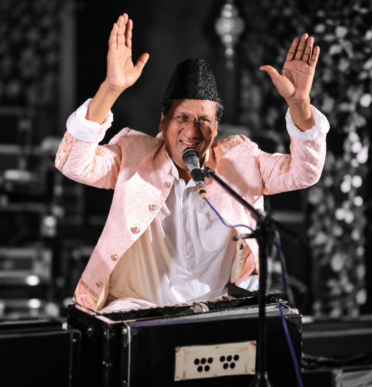 Ustad Chand Nizami performing at the harmonium with both hands raised